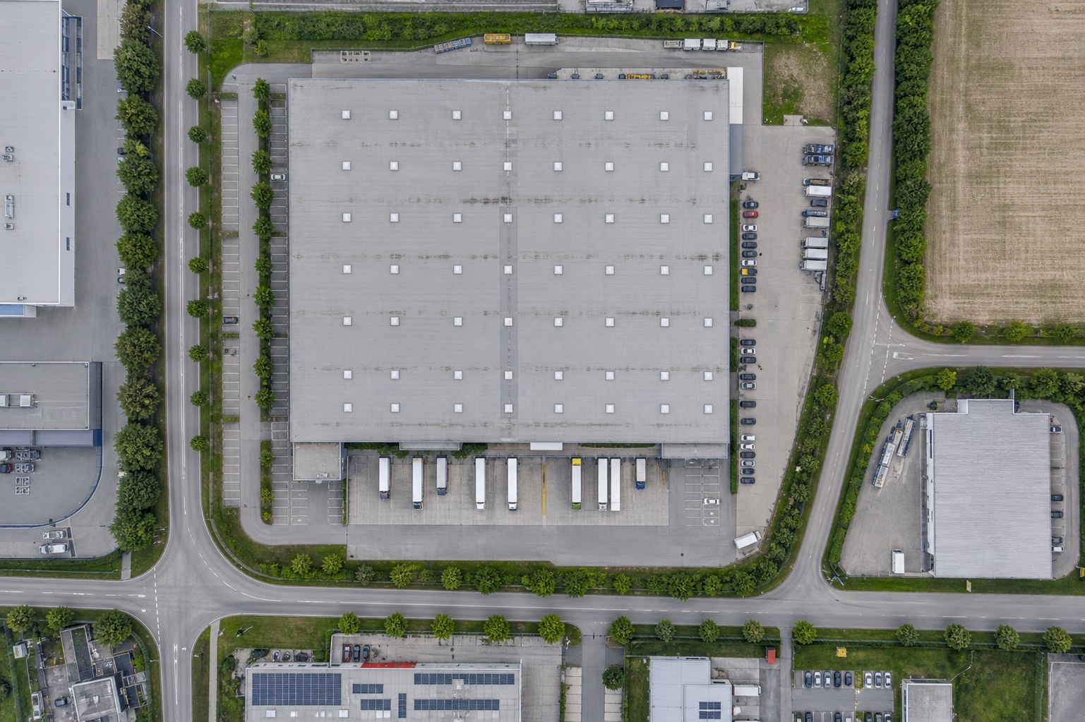 Illustrative senkrechte Ansicht einer Lager- und Logistikhalle mit Ladehöfen, Lkw, Stellplätzen und Zufahrten